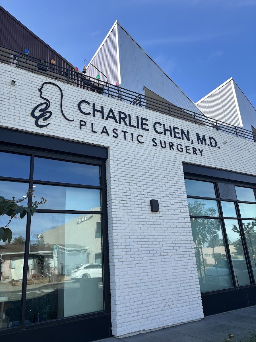 Exterior of Charlie Chen, M.D. Plastic Surgery in San Diego, with the practice name and logo across white brick against a clear blue sky