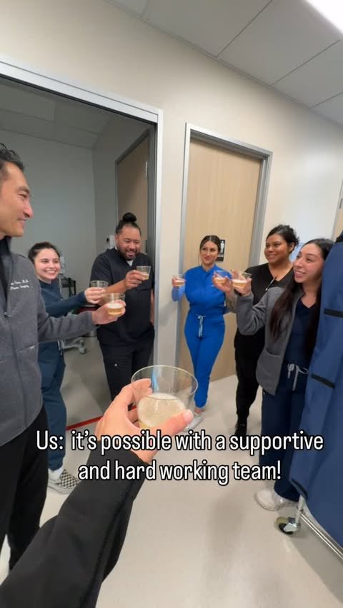Dr. Chen and his staff in scrubs raising glasses in a toast inside the new surgery center hallway